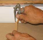 A piece of wood the width of the scribe on the adjacent wall jogs the divider pencil so the countertop will match the uneven walls on an inside corner countertop.