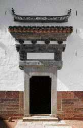 Yin Yu Tang's formal entrance penetrates a stone and brick masonry curtain wall.