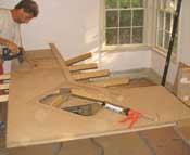 Glue and screw 2-1/2-inch build-up strips along the front and rear edges. Use full-width pieces at least 2 feet wide to span over joints in the surface piece. Add cross strips where cabinets meet.