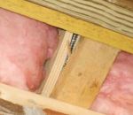 The 2-by blocking used to reinforce this cantilevered I-joist has been split by the lag screw connecting a PT deck ledger to an engineered rim joist. Under substantial load, the split blocking will tear off the bottom flange of the I-joist and cause the remaining I-joist section to fail.