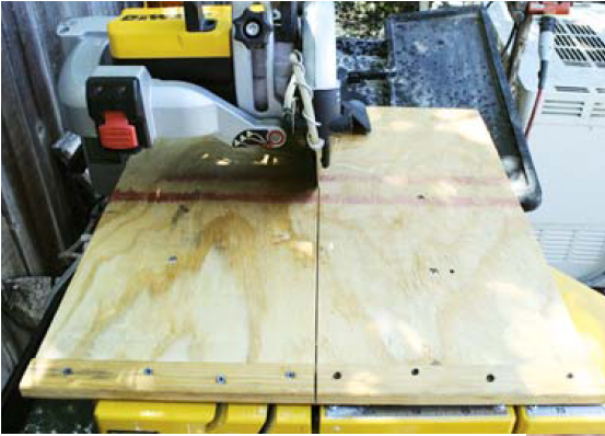 A plywood table clamped to the tile saw’s bed.