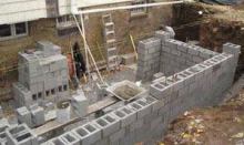 To strengthen the block foundation, workers placed rebar in all the corners, grouted the cores, and used Dur-O-Wal wire mesh on every other course. A pilaster of interlocking block reinforced with rebar at the midpoint of the longest wall provided additional lateral strength.