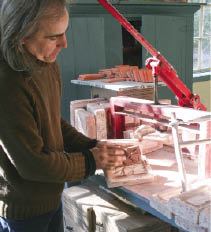 To form a tile, Hopkins packs raw clay into a custom mold and compacts it with a press, then slices off any excess with a wire frame knife.