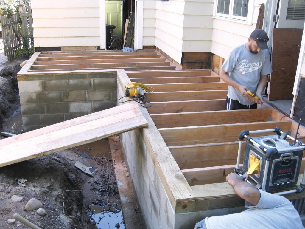 When excavating for the foundation of the addition, the author used the top of the floor joists at the center of the future opening between the addition and the existing house as the benchmark. After forming and pouring the 12-inch-deep by 24-inch-wide footing, the crew laid up the wall using 12-inch-wide concrete block, terminating the top of the wall with a course of 8-inch block. This created a 4-inch-deep inner shelf that was topped with a 4x6 PT mudsill set on edge.