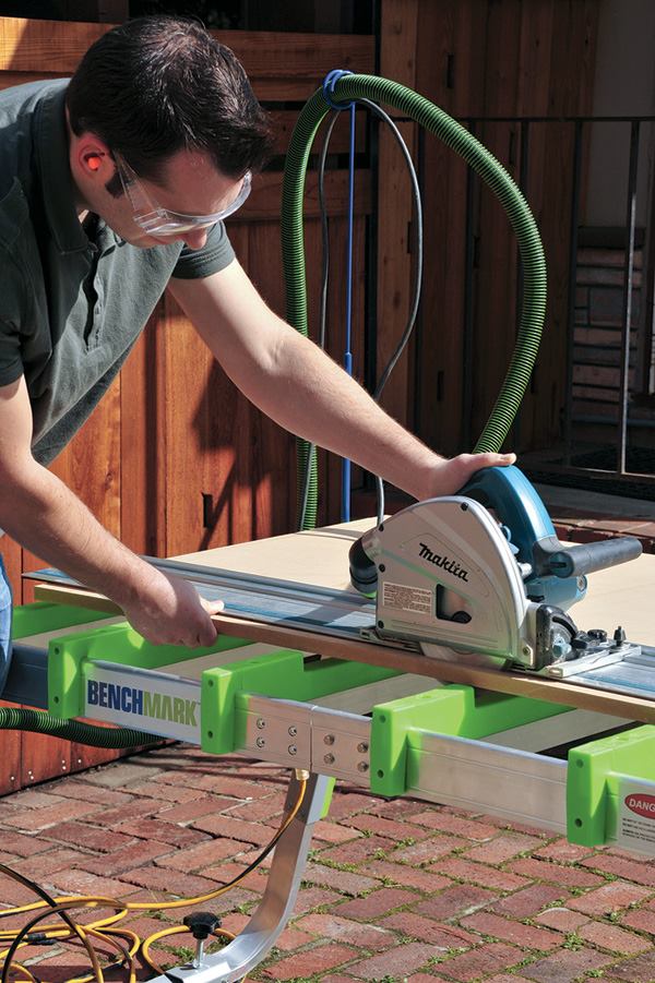 Having positioned the stock with the cut line over the recessed part of the crossbars, the author rips it without fear of cutting into the surface below. The recesses can also be used as stops when cross-cutting narrow material with a hand-held saw.