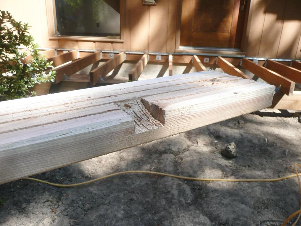 In the bottom of the deck board that’s next to the house, and again in the board adjacent to the fascia, the author cuts grooves that will land above each set of joists so that water can drain away.