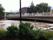 Boulder Creek rising under a bridge in downtown Boulder. Deep beneath the floodwaters are multiple lanes of bike and walking paths and a tall scenic waterfall.