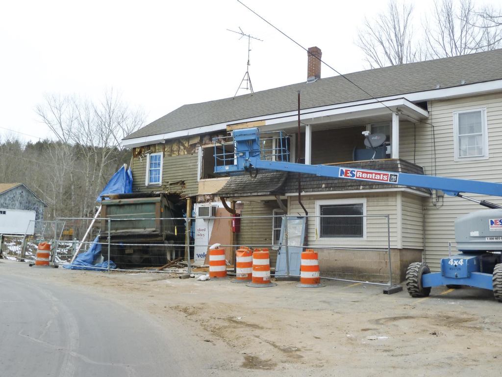 With its uncanny knack for backstopping out-of-control vehicles, the historic New Boston Store has provided repair work for generations of local carpenters. It’s located at a sharp bend in the road, tight against a bridge.