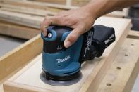 A push-button switch starts the tool and toggles through high, medium, and low speeds (the other button stops the tool). The sander takes 5-inch 8-hole hook-and-loop disks.