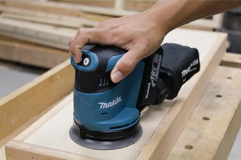 A push-button switch starts the tool and toggles through high, medium, and low speeds (the other button stops the tool). The sander takes 5-inch 8-hole hook-and-loop disks.