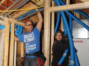 In this composite split image, Placetailor carpenter Diego Gutierrez (left) guides air lines through the ceiling framing while project manager Travis Anderson (right) pulls the lines into place at the Air Pohoda heat exchanger and air handler.