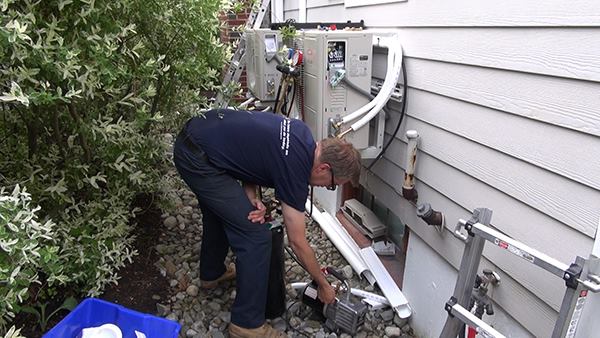 Master plumber Dave Ragsdale purges the refrigerant lines of a 12,000-Btu Fujitsu mini-split heat pump. In tandem, the solar panels and heat pumps will relieve the home's existing oil boiler of much of its annual job.