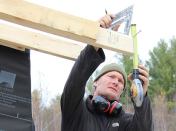 Contractor Jesper Kruse figures the fascia width on a rafter tail, taking into account the thickness of roof strapping not yet applied.