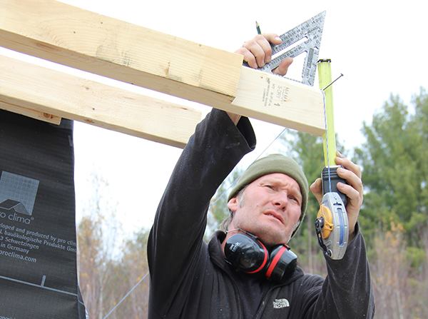 Contractor Jesper Kruse figures the fascia width on a rafter tail, taking into account the thickness of roof strapping not yet applied.