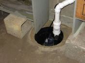 The same drain pipe used in the sculpture forms a pit for a sump pump.