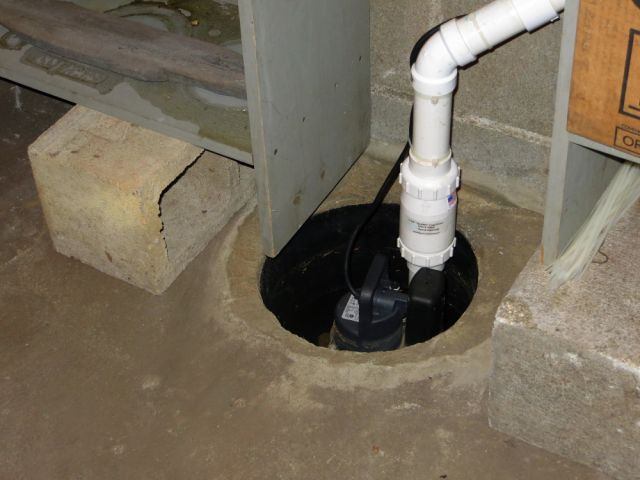 The same drain pipe used in the sculpture forms a pit for a sump pump.