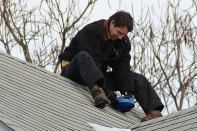 ReVision Energy's Phil Coupe checks the solar exposure of a rooftop on Peaks Island, in Portland, Maine. Solar arrays combined with mini-split air-source heat pumps have helped some island residents drastically cut back their consumption of costly heating oil.