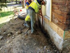 A “water knife” (a power washer) is used to slice a narrow slot around the perimeter of a house in Minneapolis. The Building America project successfully demonstrated that exterior foundation insulation can be cost-effectively retrofitted on existing homes to boost energy savings and help control moisture migration through the foundation.