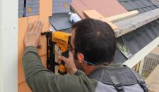 Project lead Mark Pollard nails factory dipped white cedar shingles over 3/8" MortairVent drainable fabric. Shingles are held 1 inch above the flashing and roofing to promote drainage and to allow an inlet for air into the rain screen assembly.