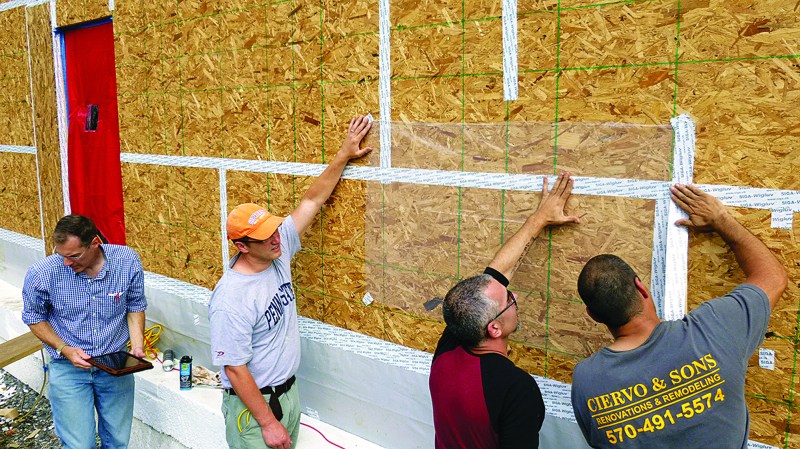 Architect Richard Pedranti, HERS rater Pete Vargo, consultant Bryan Kehm, and builder Rob Ciervo tape plastic over the OSB sheathing during a blower-door test.