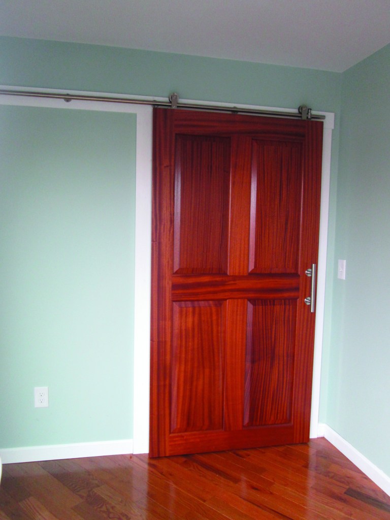Using portable power tools on a simple jobsite setup, it’s possible to make a custom door slab. The trick is creating a strong joint between the stiles and rails, which is done here with a Festool Domino. The author built this sliding passage door out of Utile, an African ribbon-stripe mahogany.