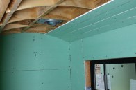 To shed water properly, bathroom ceilings should never be flat. Here the ceiling is arched and a tight grid has been framed to support the tile. Strips of green board form the initial arched surface.