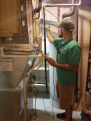 The author uses a manometer probe to test the draft pressure in a water heater vent. This step should be performed routinely for safety and quality assurance any time the mechanical room equipment is serviced, and whenever weatherizing work or remodeling may have affected combustion appliance vent performance.