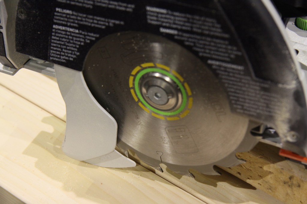 A riving knife is integral to the blade guard, minimizing binding and kickback.