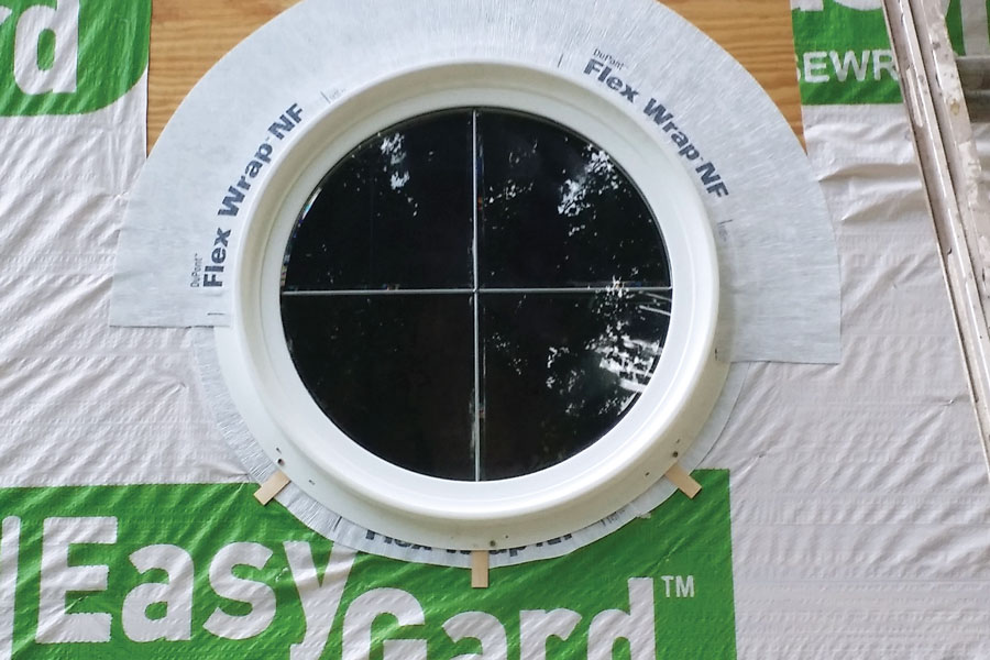 A flexible butyl-based flashing material works well for flashing roundtop windows, but the sill is tricky. In this case, the installer has left the bottom uncaulked and added shims to promote drainage.