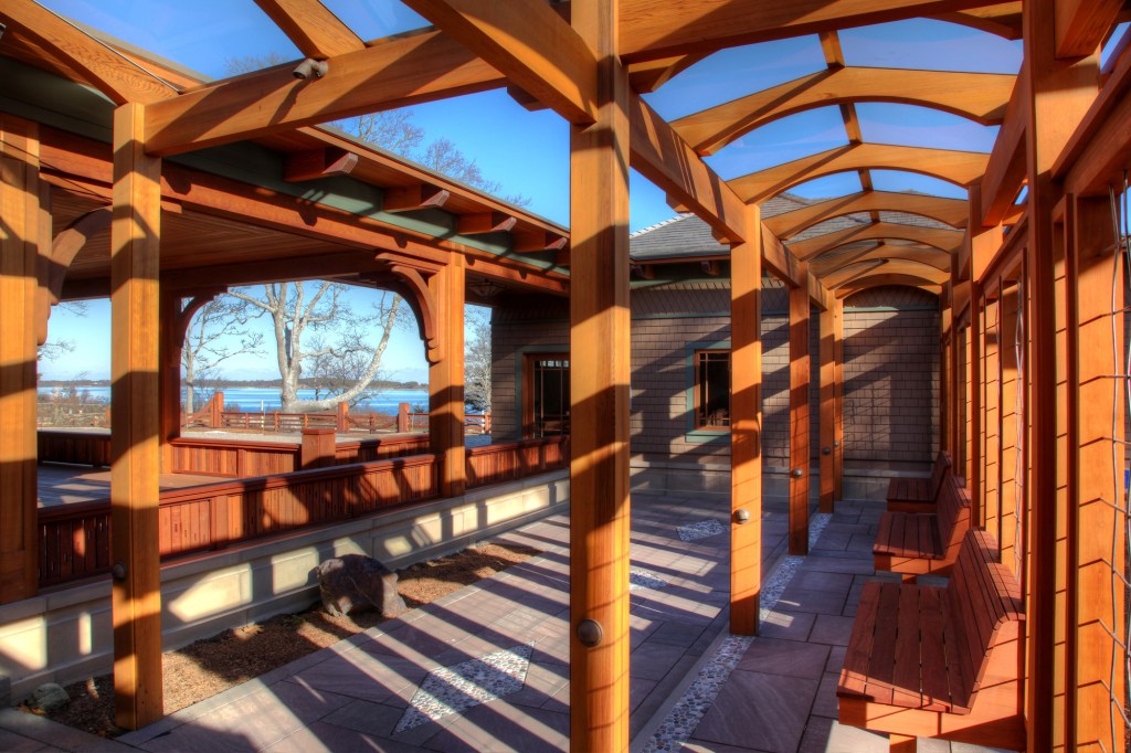 On a Craftsman-style home on Cape Cod, arched, red-cedar cross beams support a glass covering for this arbor.