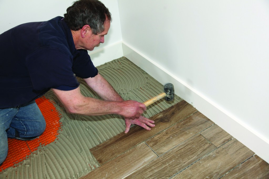 After combing the thinset out in one direction, press the tile into the thinset and tap with a rubber mallet.