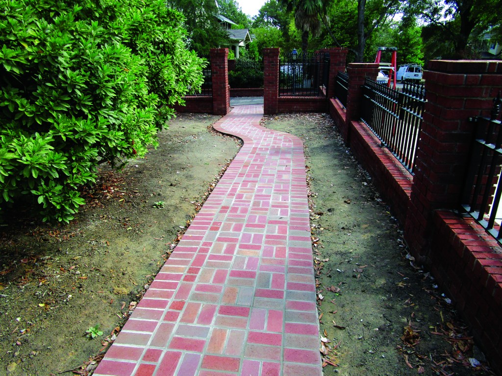 This brick walk, along the side of the house, needed to shift position from the existing brick-pillar entry to run safely around mature shrubs growing next to the house. The author chose an S curve to transition between the two sections of sidewalk.