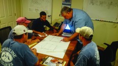 The architect and the building crew  met to question and  review the details  of a challenging  project to make sure  everyone was on the  same page before  the project began.