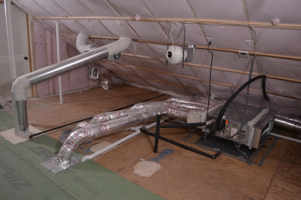 An encapsulated, semiconditioned attic houses the mechanicals for one of the author’s highperformance homes. A fan-powered freshair intake draws in a continuous 20 to 30 cfm. Below that, a five-zone air handler distributes conditioned air to occupied rooms below. Behind the sloping kitchen exhaust duct is a makeup air intake, which opens whenever the kitchen exhaust vent downstairs creates a negative pressure.