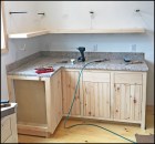 The author was tasked to install a pair of “floating” corner shelves, which he accomplished by building hollow shelves mounted on 1/2-inch square steel dowels.