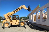 The author uses a telehandler to lift a partially built LVL beam into place. The beam was needed to support second-floor framing over a large, open-plan first-floor living room.