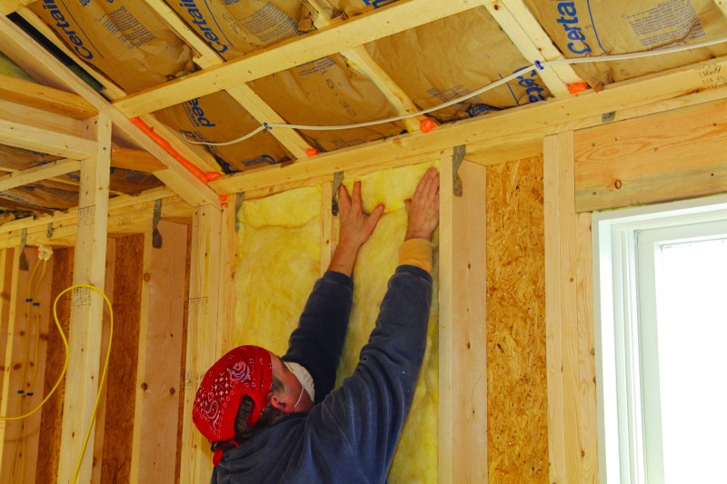 To insulate effectively, fiberglass batts need to fill the entire stud bay without being compressed. To insulate a wall, start by filling the full-width bays. Insert the batt from the top down, pushing it up against the wall plates. If the sides snag on rough lumber, run a putty knife along the side of the stud.