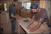 Dean Moran (right) and Thomas Moses of Artisan Builders apply adjustable cabinet levelers to site-built cabinets in Orleans, Mass.