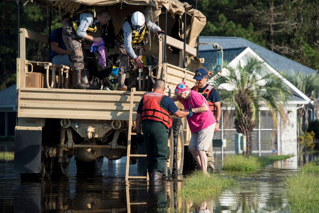 Coast Guard members assigned to the Atlantic and Pacific Strike Team assist an elderly woman into an Army National Gaurd high-water transport vehicle Sept. 20, 2108, in a flooded neighborhood in Longs, South Carolina. (U.S. Coast Guard photo by Petty Officer 3rd Class Ryan Dickinson)