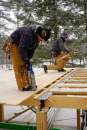 Carpenters Alex Strugatskiy (left) and Ryan Bielenda apply tongue-and-groove pine ceiling boards to sawn timbers as they deck over a lower-level living space for a pond-side home in the Maine woods.