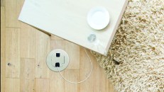 Children are sitting at opposite ends of a sofa in the living room of their home. They are wearing pyjamas and are playing around together.