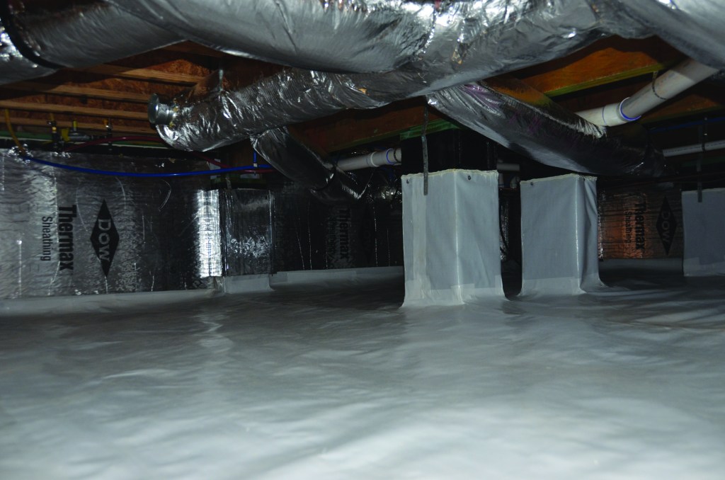 A view of an Addison  Homes “encapsulated”  crawlspace, showing the  company’s current standard  features: a 20-mil poly  ground cover; 1.5-inch foilfaced  insulation on the walls;  and an “inspection strip” at  the top of the block walls to  allow termite inspections.  The masonry-wall top is  coated with waterproofing  to prevent vapor intrusion.