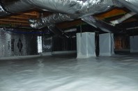 A view of an Addison  Homes “encapsulated”  crawlspace, showing the  company’s current standard  features: a 20-mil poly  ground cover; 1.5-inch foilfaced  insulation on the walls;  and an “inspection strip” at  the top of the block walls to  allow termite inspections.  The masonry-wall top is  coated with waterproofing  to prevent vapor intrusion.