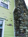 Honey bees were entering the wall cavity through a large cap along the stone chimney.