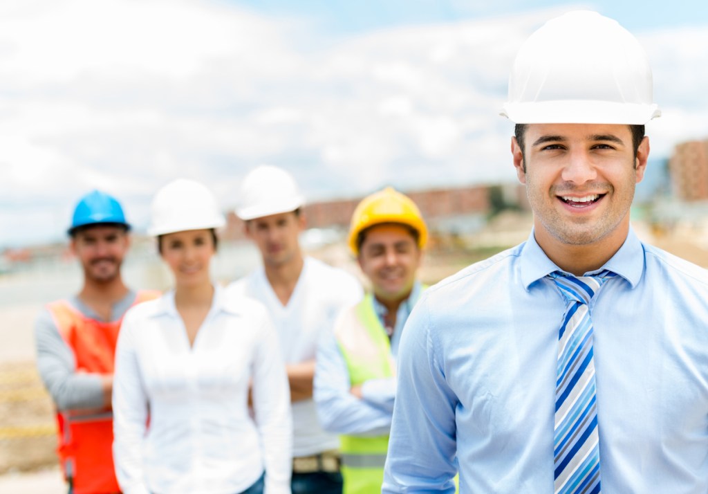 Portrait of a handsome architect with his teamwork in the background