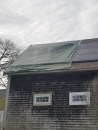 Four days after the fire, a contractor secured a tarp over the damaged roof and panels as storm clouds gathered overhead.
