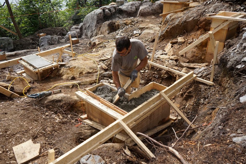 Mark Pollard consolidates concrete for a foundation pier on a rocky site in Maine.