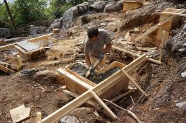 Mark Pollard consolidates concrete for a foundation pier on a rocky site in Maine.
