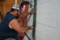 Toby Bonilla of Great Lakes Builders smooths out the two-part epoxy over a carbon-fiber strap used to reinforce a block foundation wall.