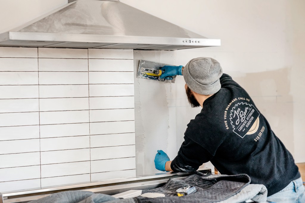 In this photo (above), the author tiles a backsplash. (The completed kitchen is shown further down in this article.) . His company, Jon Beer Contracting, self performs almost everything it can to control quality.